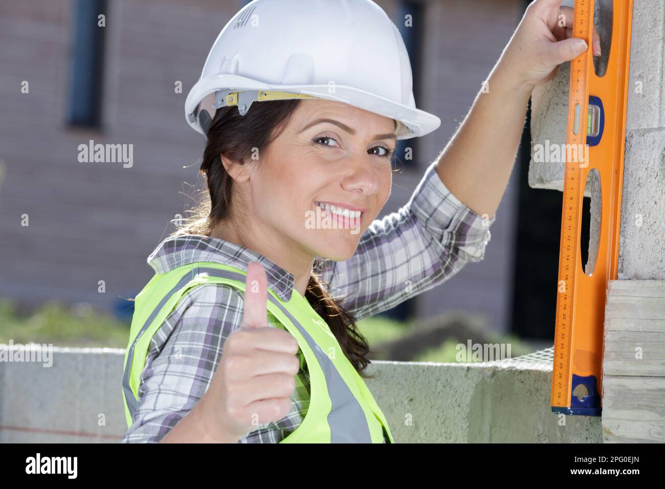 female builder using spirit level outdoors Stock Photo