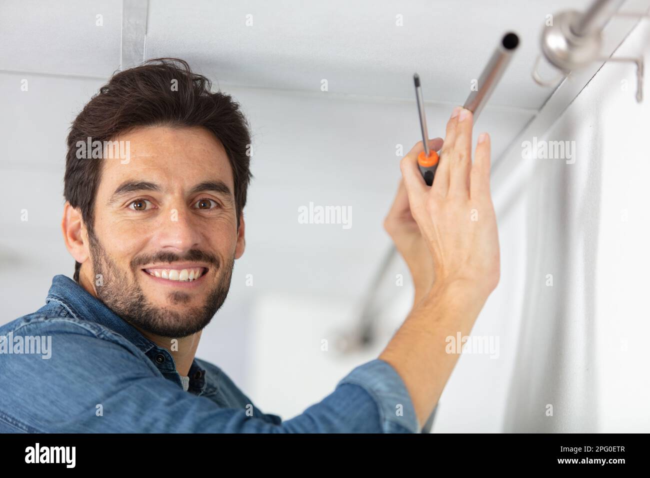 young man installing curtains over window Stock Photo