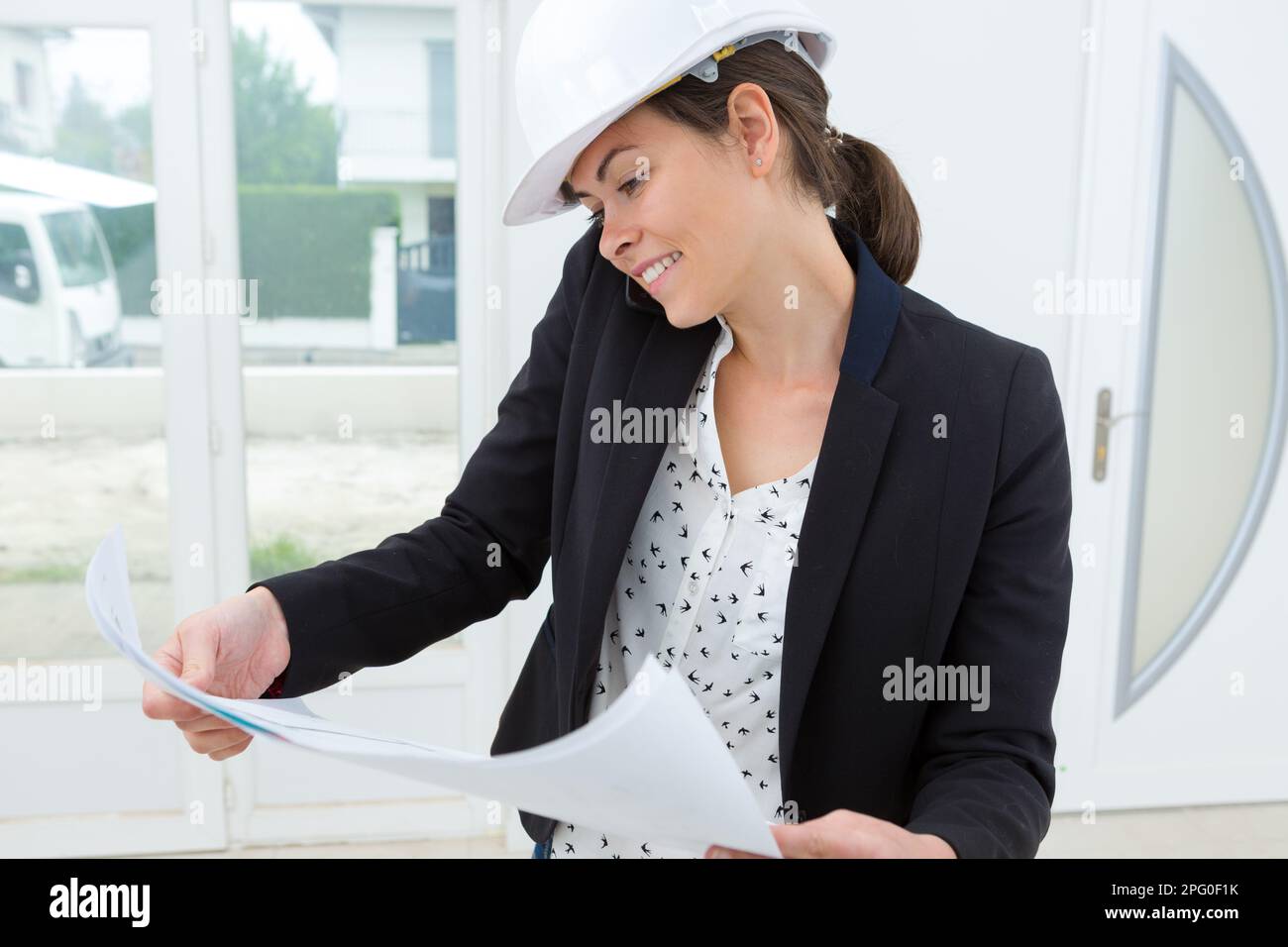 female architect smiling while looking at blueprint Stock Photo - Alamy