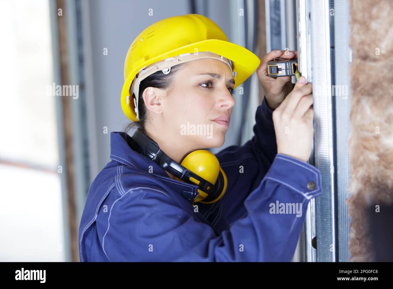 workwoman is checking dimensions of finished metal window Stock Photo