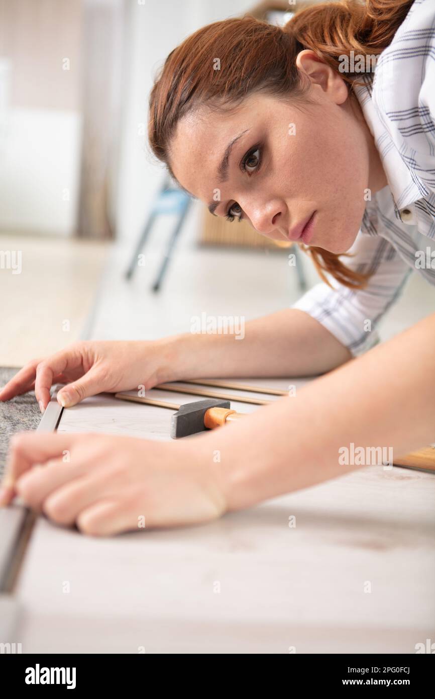 female repairman installing and measuring roll of carpet Stock Photo