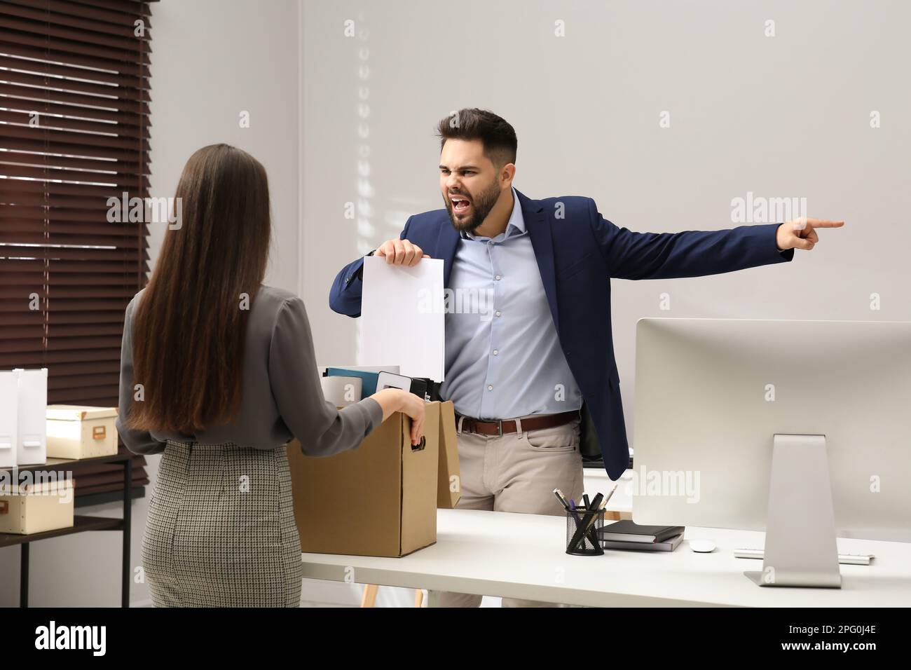 Boss dismissing young woman from work in office Stock Photo