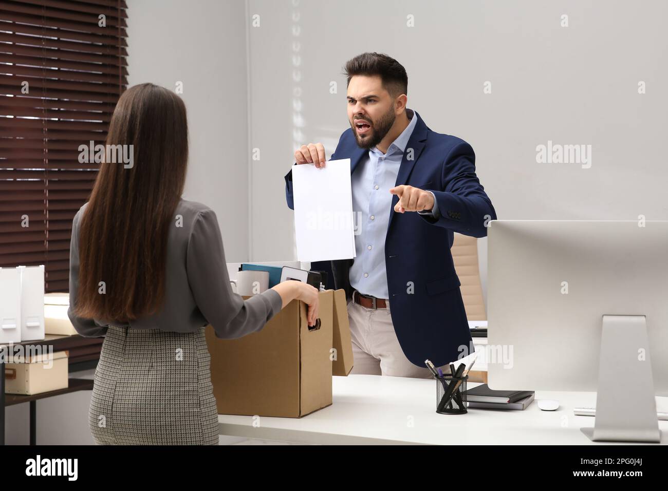 Boss dismissing young woman from work in office Stock Photo