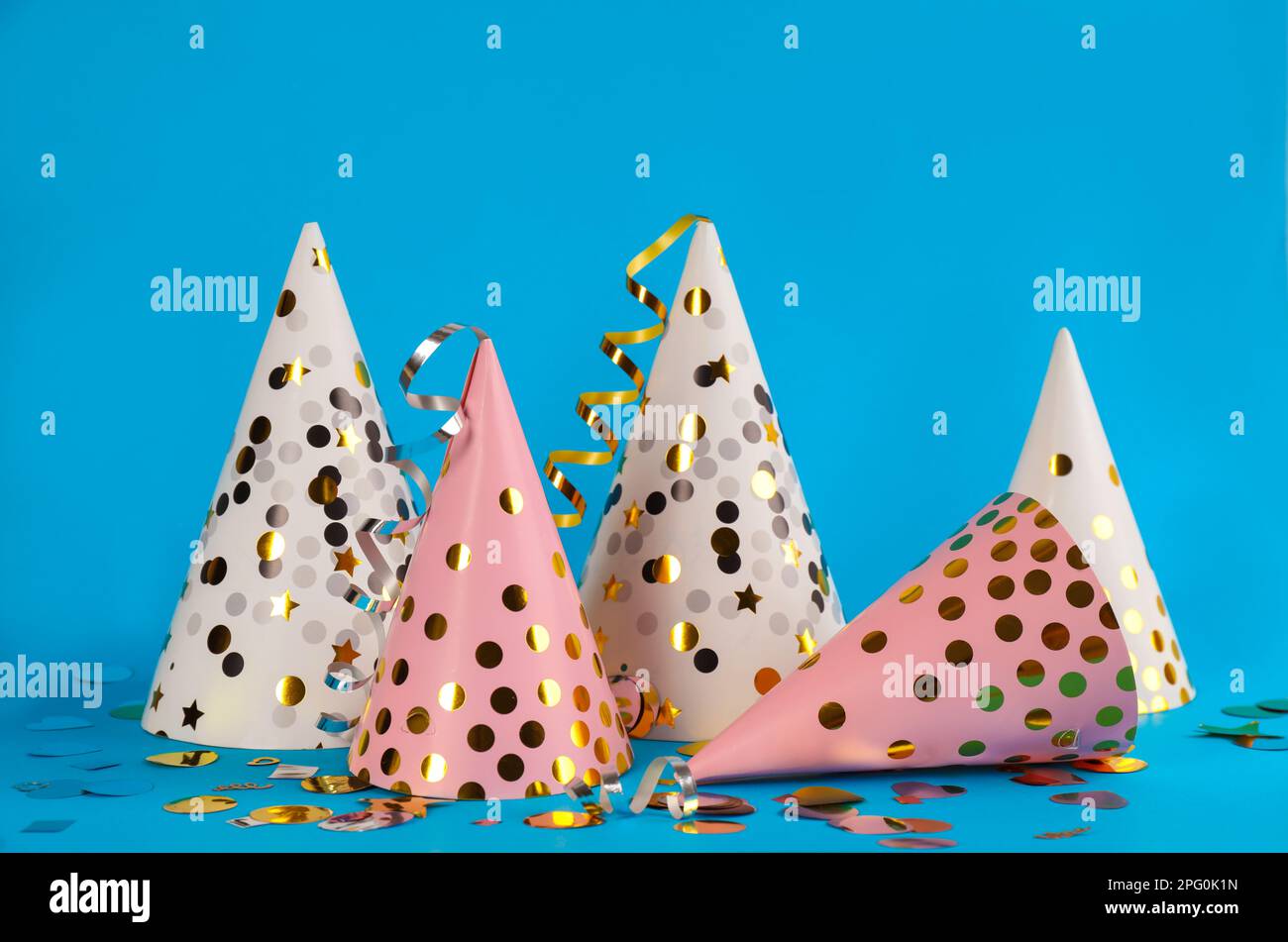 Colorful party hats and confetti on light blue background Stock Photo ...