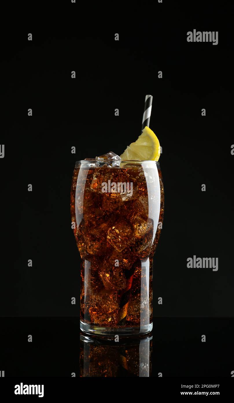 Glass of refreshing soda water with ice cubes and lemon slice on black ...