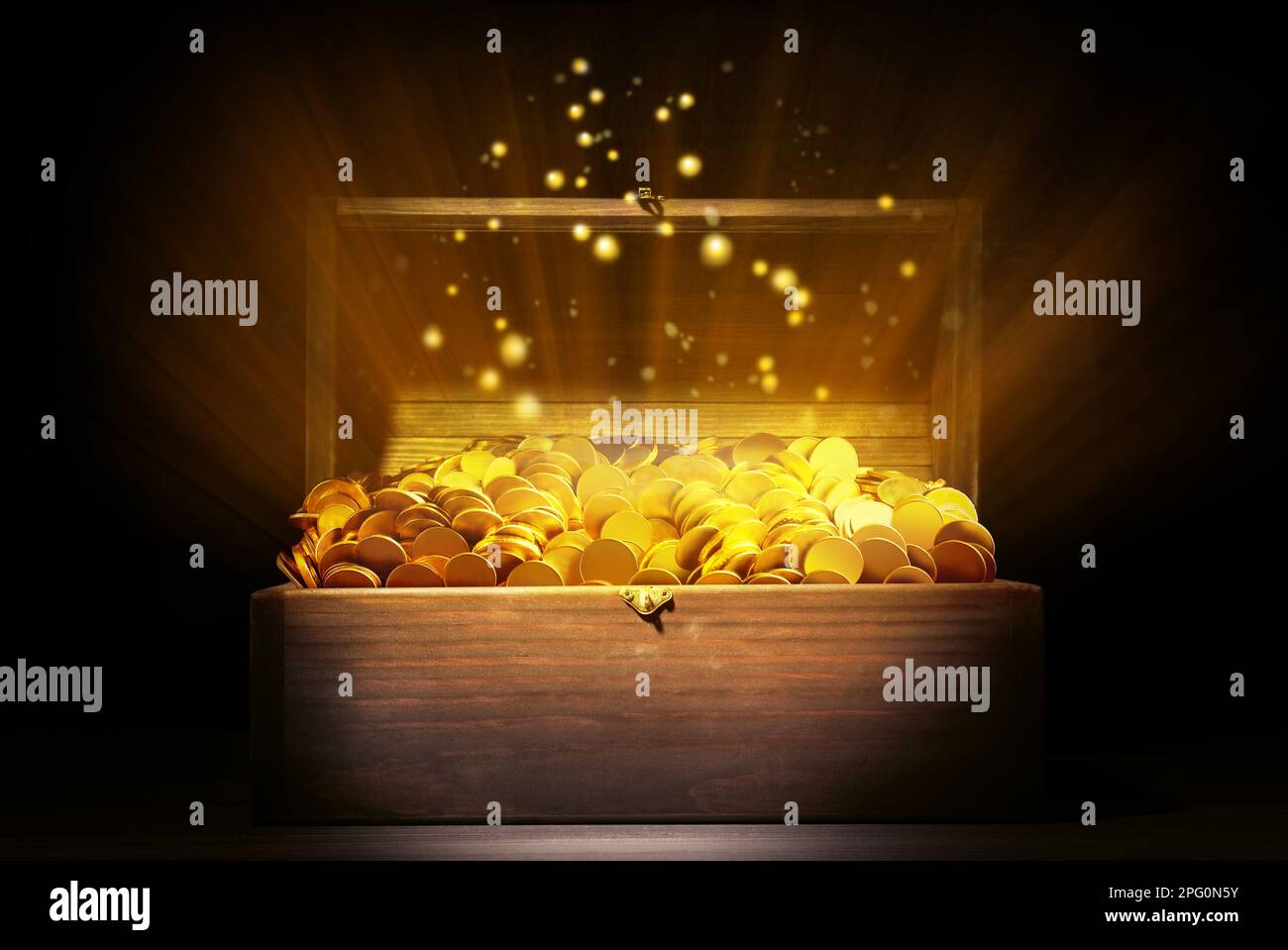 Open treasure chest with gold coins on table against black background