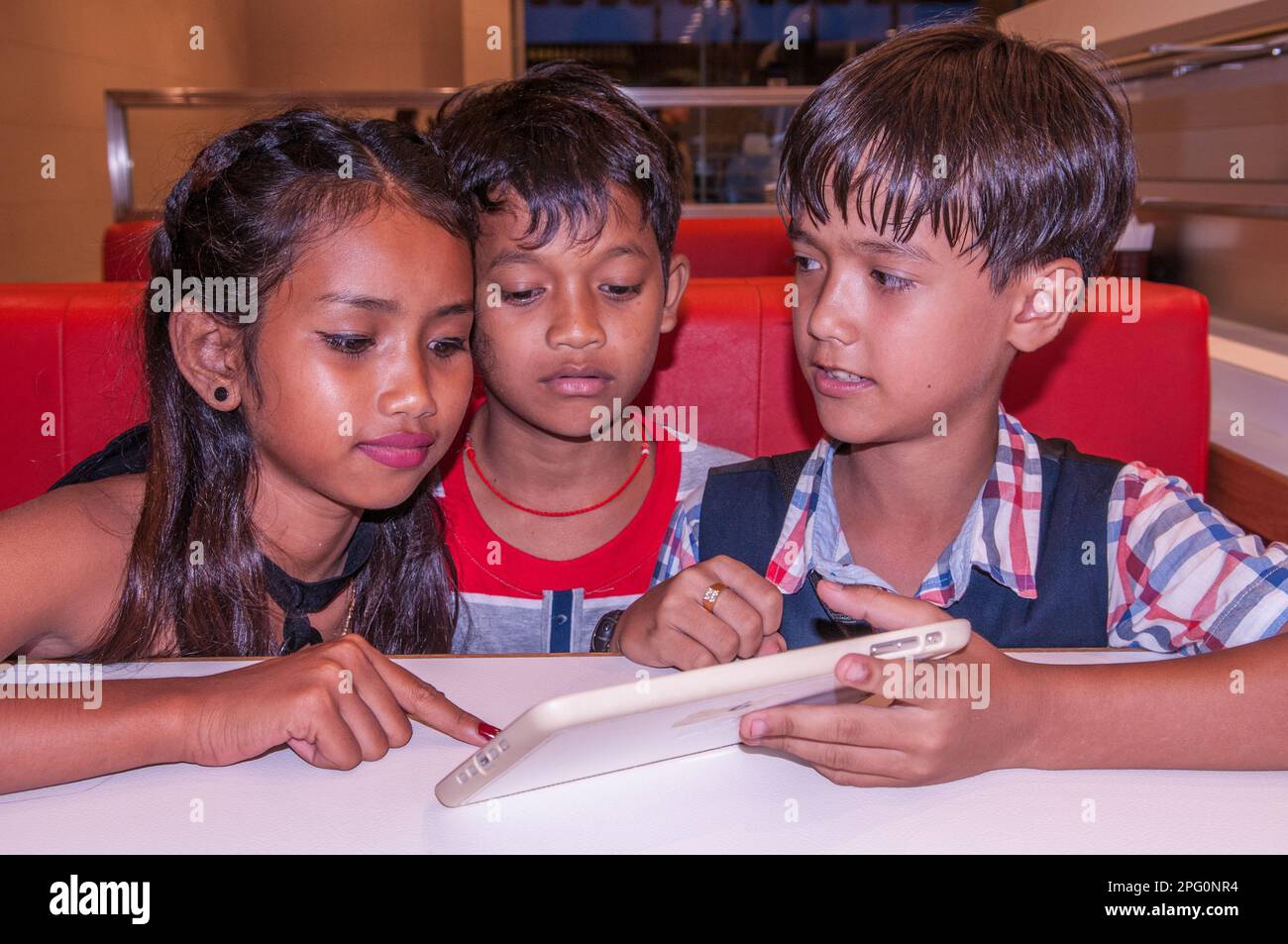 3 adorable children, tweens, 2 Khmer kids & 1 mixed race boy (Cambodian - American) choose their food. Phnom Penh, Cambodia. credit: Kraig Lieb Stock Photo