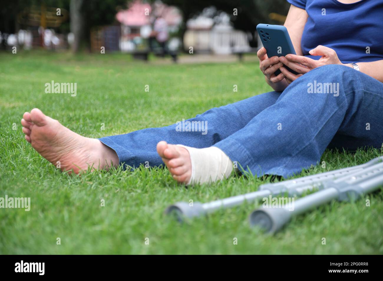 Unrecognizable woman resting on the grass using her smartphone
