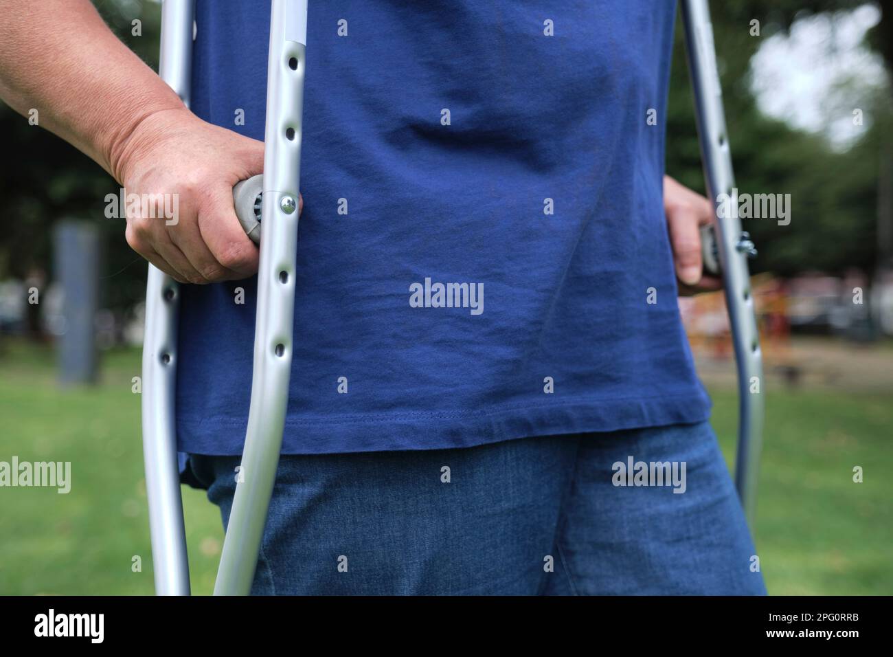 Unrecognizable woman walking outdoors with the help of crutches in the