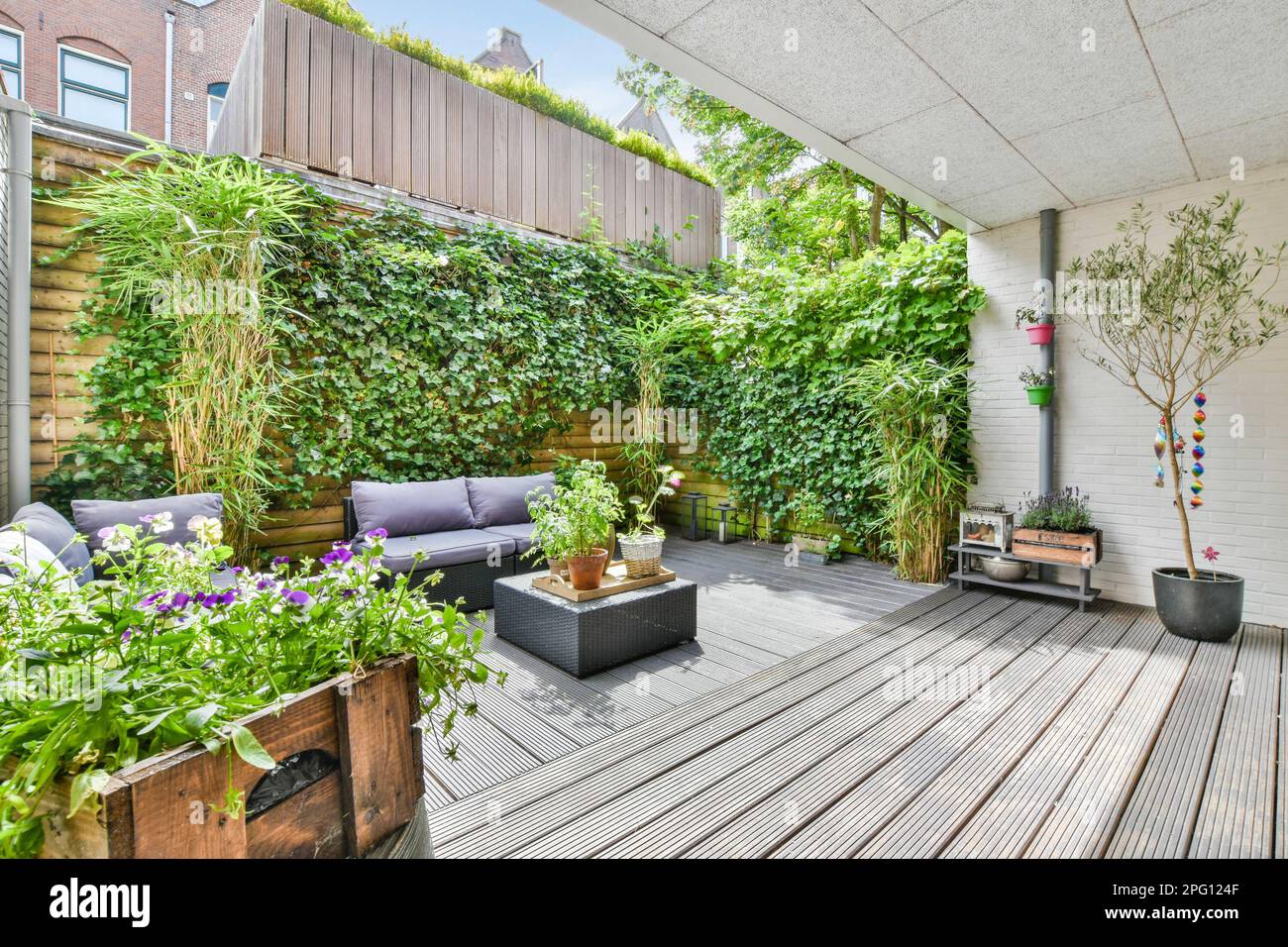 an outdoor living area with wooden decking and potted plants on the ...