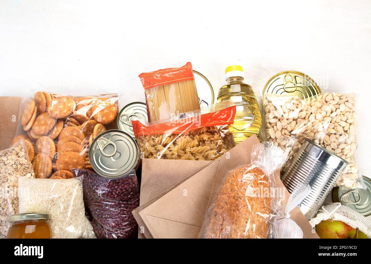Food donations with pasta, rice, oil, peanut butter, canned food, jam and other  on light background, top view with copy space. Food donations or deli Stock Photo