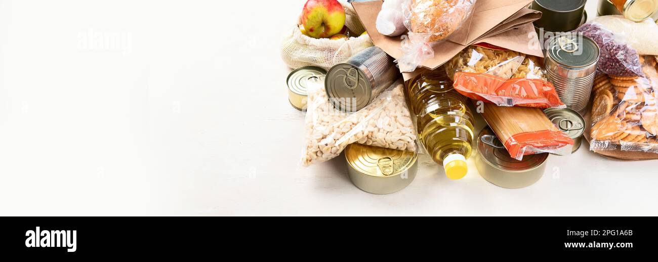 Food donations with pasta, rice, oil, peanut butter, canned food, jam and other  on light background, panorama, banner with copy space. Food donations Stock Photo