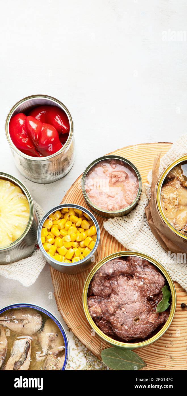 Various canned vegetables, meat, fish and fruits in tin cans. On a white background. Top view. Stock Photo