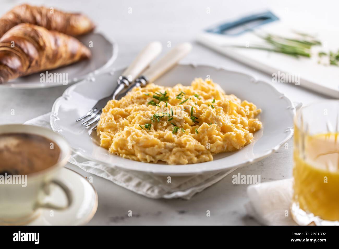 Breakfast served with a plate of scrambled eggs, croissants, orange juice and cofffee. Stock Photo