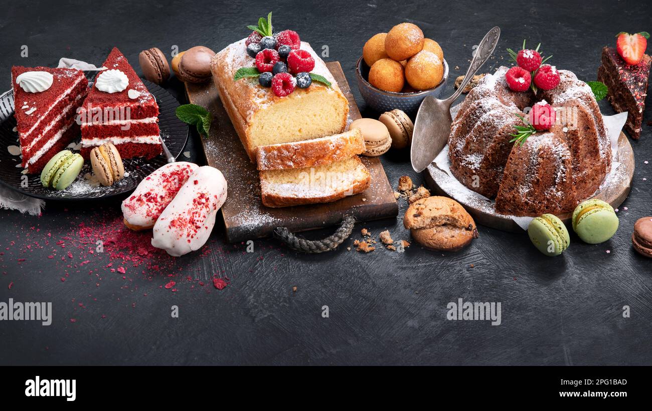 Different desserts on dark background. Delicious sweet dessert table with pound cake, chocolate and red velvet cakes. Holiday  sweet eating concept. Stock Photo