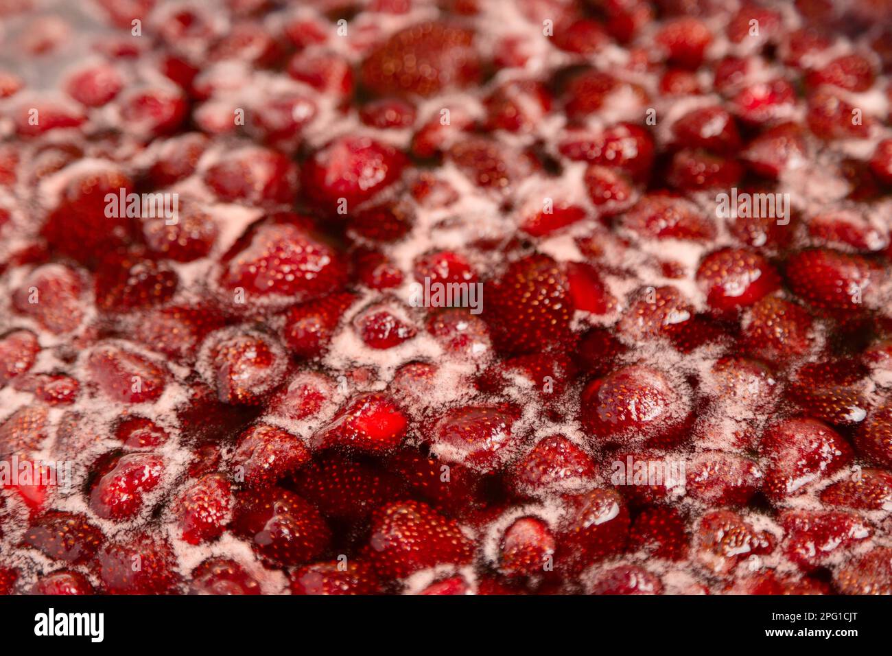 Strawberry jam simmering slightly, detailed close-up, top view. Beautiful strawberry jam in cooking process. Boiling homemade strawberry jam. Making a homemade Strawberry Jam. Boiling fruit into a pan Stock Photo