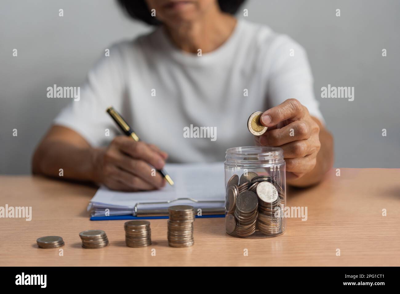 woman saving money with putting coins in glass, finance and accounting concept. Stock Photo