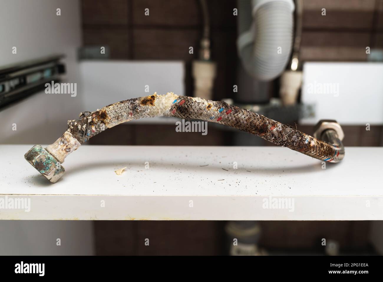 Damaged water hose with traces of corrosion, deformation of the protective layer and limescale, a concept on the topic of the timely replacement of wa Stock Photo