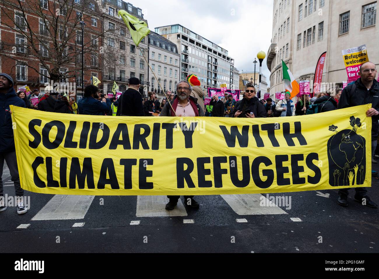 Protest taking place in London on UN Anti Racism Day. Stand up to Racism. Solidarity with climate refugees banner Stock Photo