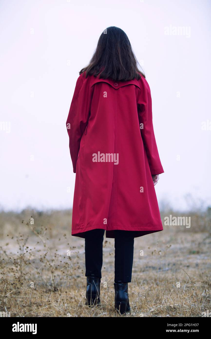 Rear view of woman in red coat walking in the field Stock Photo - Alamy