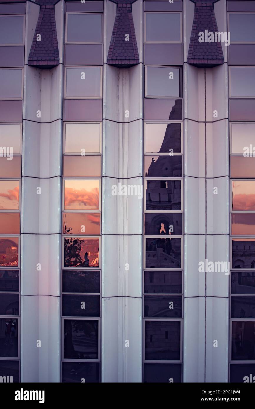 The Fisherman's Bastion in Budapest reflected in the golden glass windows of a modern business building Stock Photo