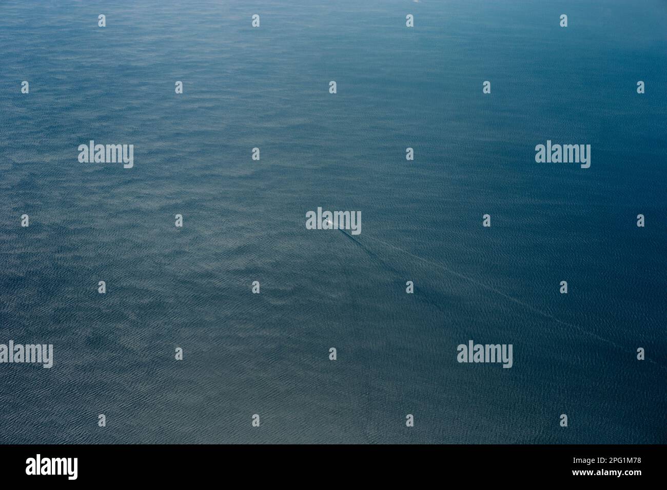 Aerial view of a solitary sailboat gliding across the open ocean ...