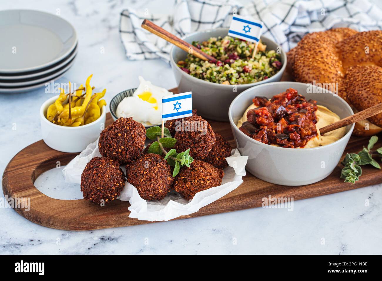 Traditional Shabbat table: challah bread, falafel, quinoa salad, hummus on a wooden board. Israeli food concept. Stock Photo
