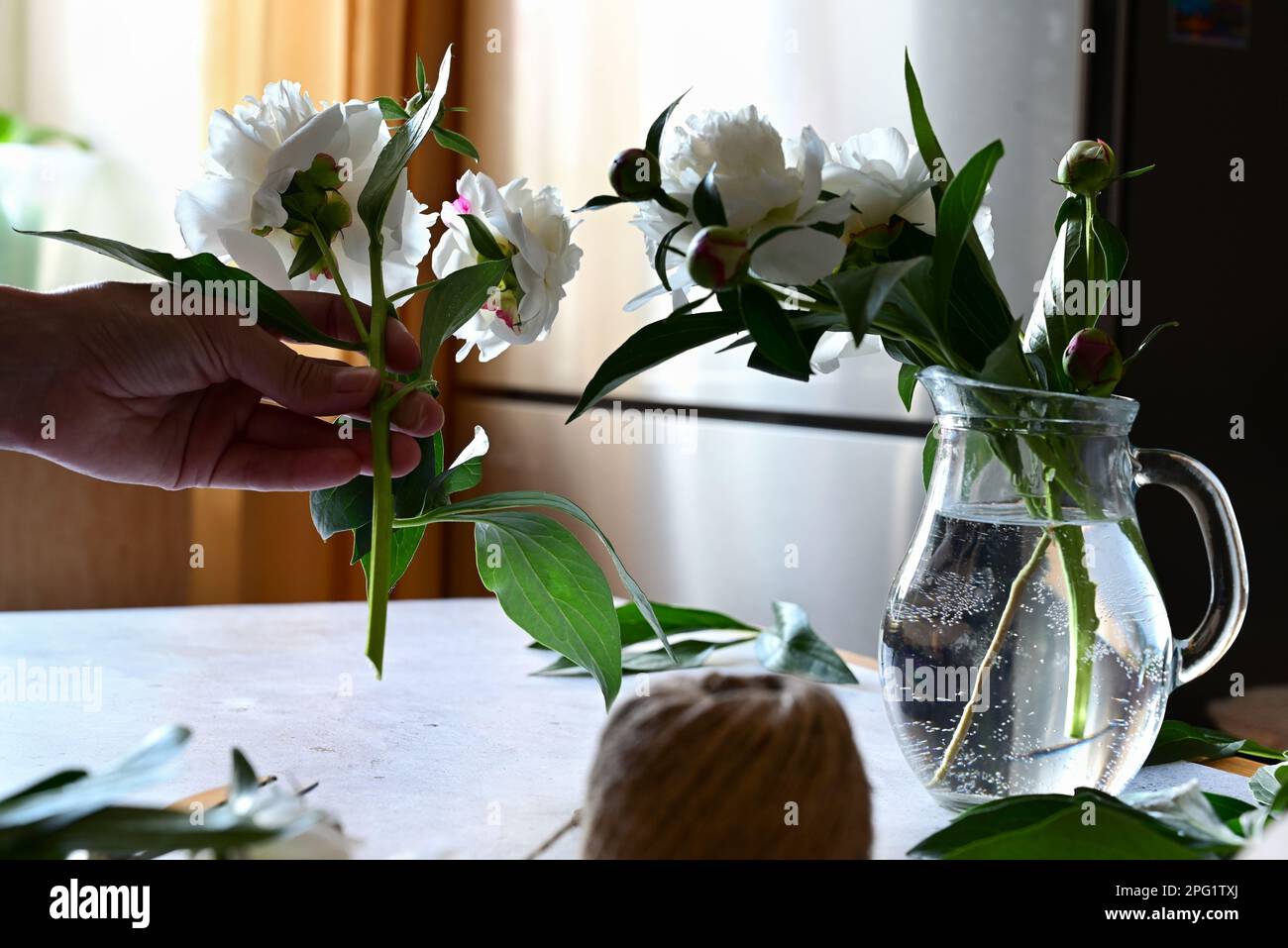 Florist makes a bouquet.a woman makes a bouquet of peonies, a bouquet of kraft paper., pruning flowers, stylite makes a bouquet Stock Photo