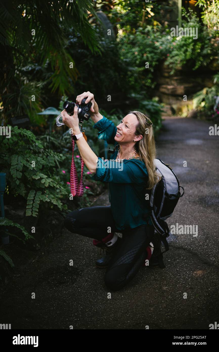 Happy woman takes photograph with camera in tropical forest Stock Photo