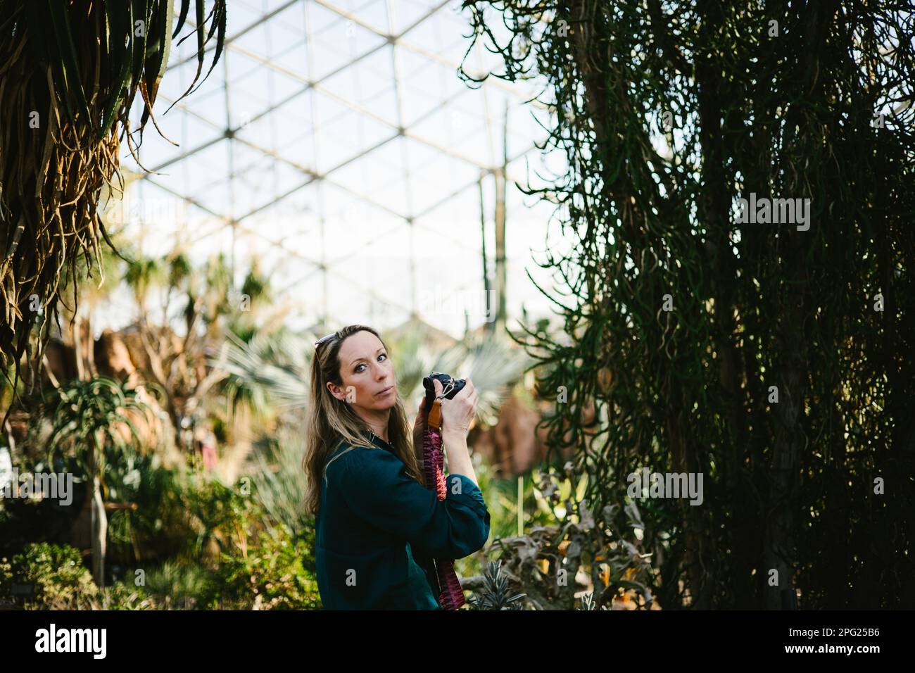 Woman with camera and eye contact in green dome greenhouse Stock Photo ...
