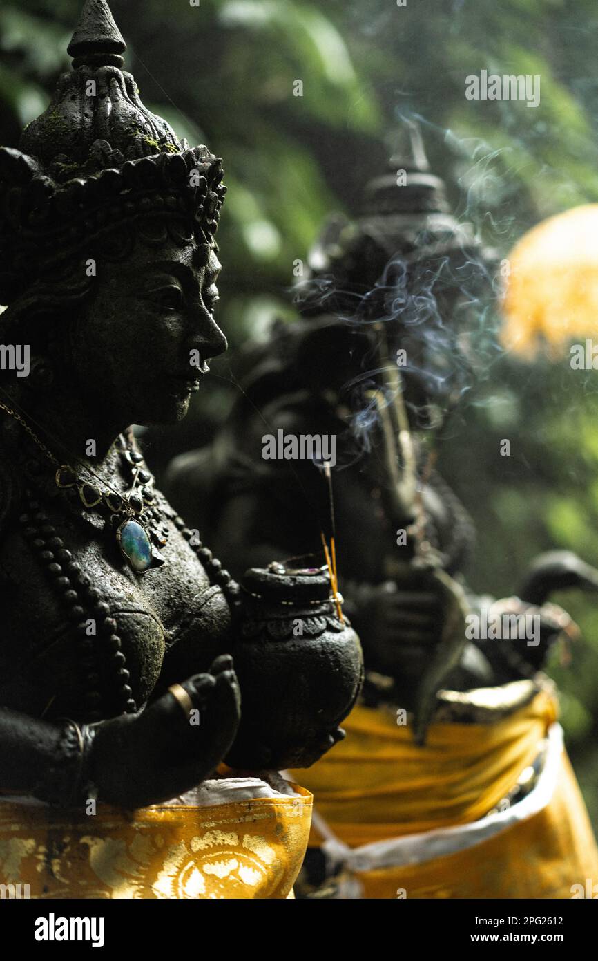 Stone statue of a Hindu god in Balinese Temple, incense smoke. Stock Photo