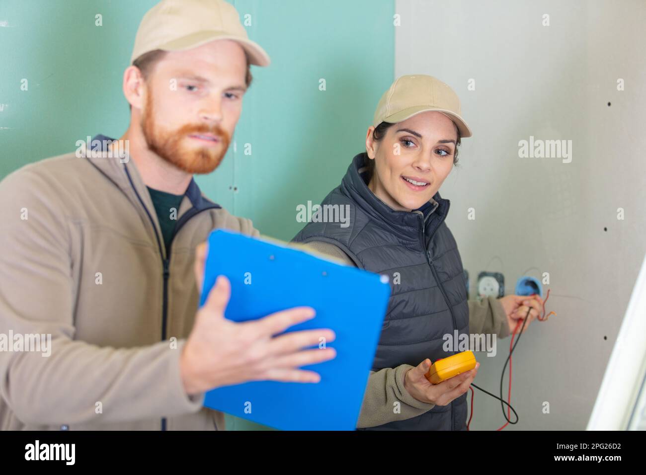 male and female electricians testing circuit with multimeter Stock