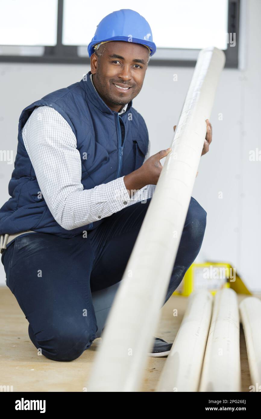 builder in a property holding a length of plastic Stock Photo Alamy