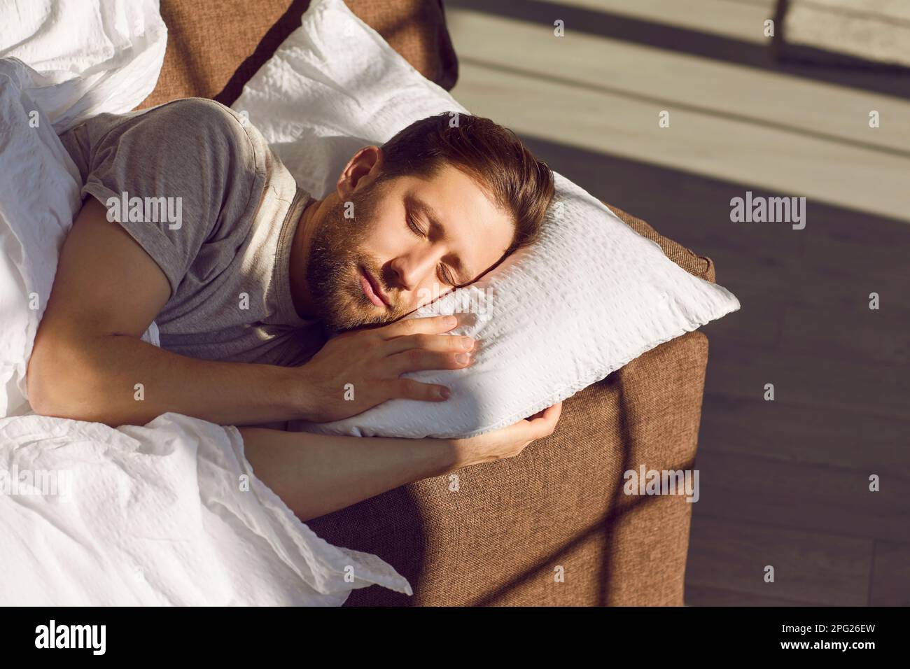 Relaxed young man is sleeping on the sofa in the bright light of the