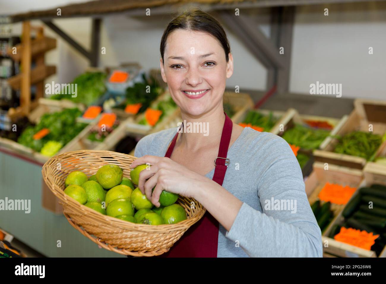 female smiling greengrocer holding a basket of lemons Stock Photo - Alamy