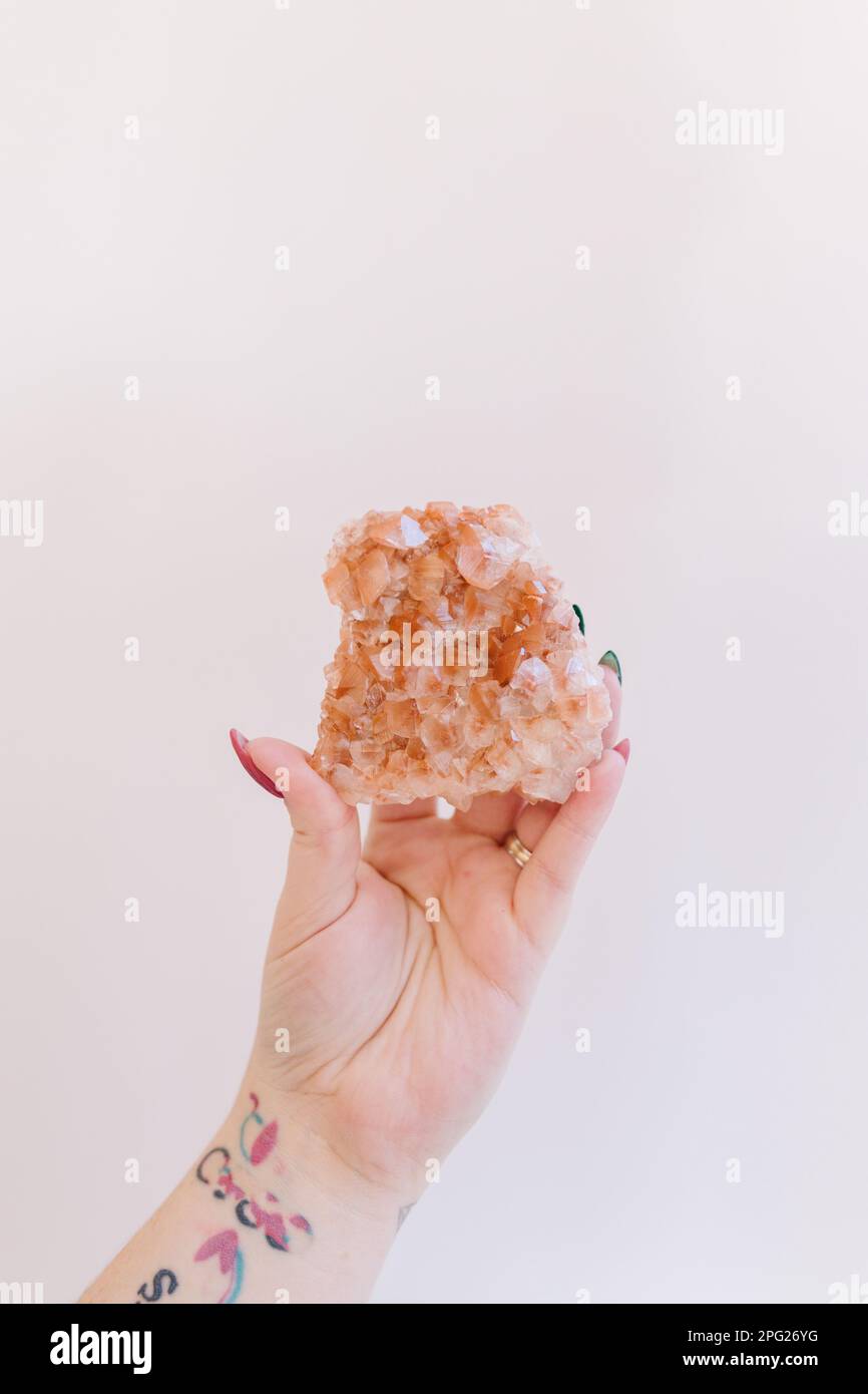 Hand holding up orange and white calcite from Hubei China Stock Photo
