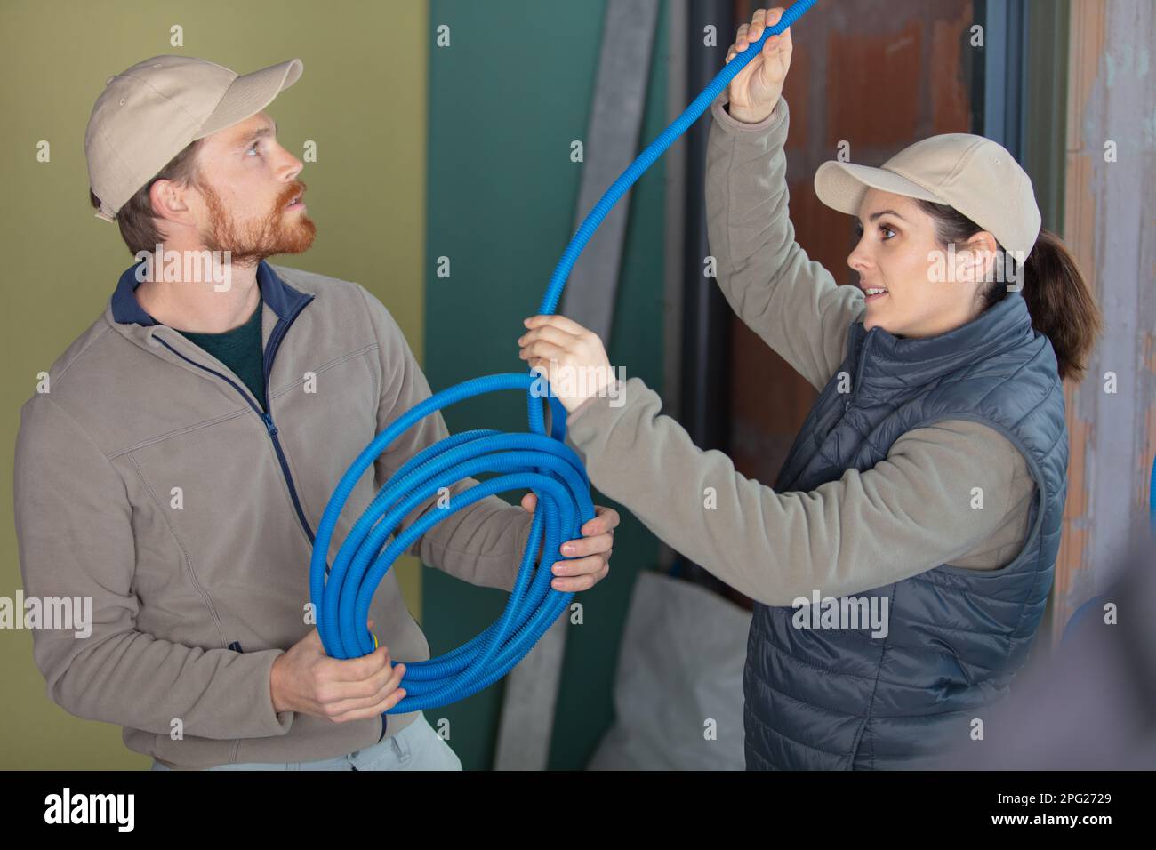 male and female builders working with blue pipe Stock Photo