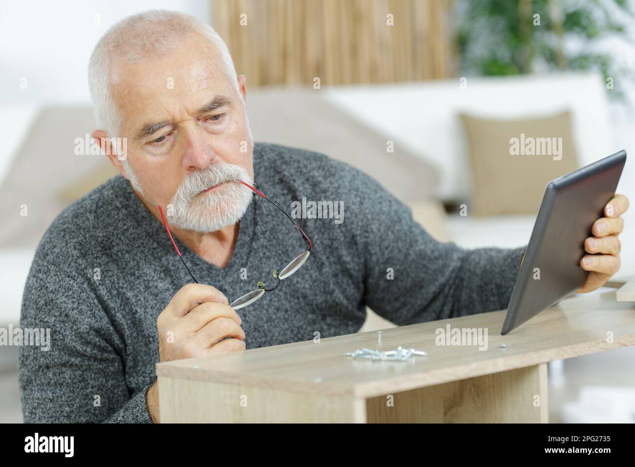 senior man using a tablet to fix a furniture Stock Photo