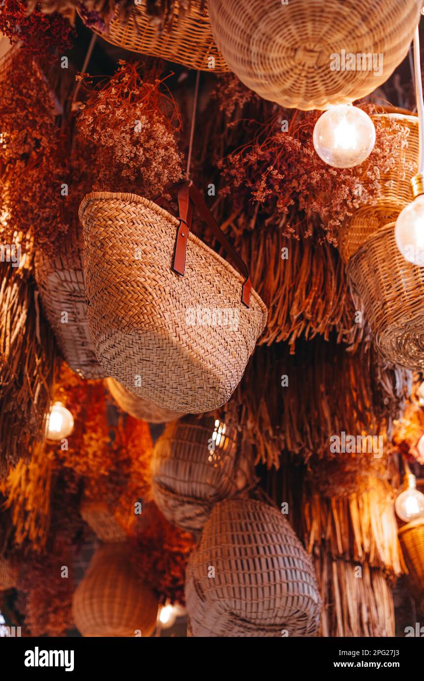 Decorations of beige straw bags and baskets hanging in the rustic interior Stock Photo