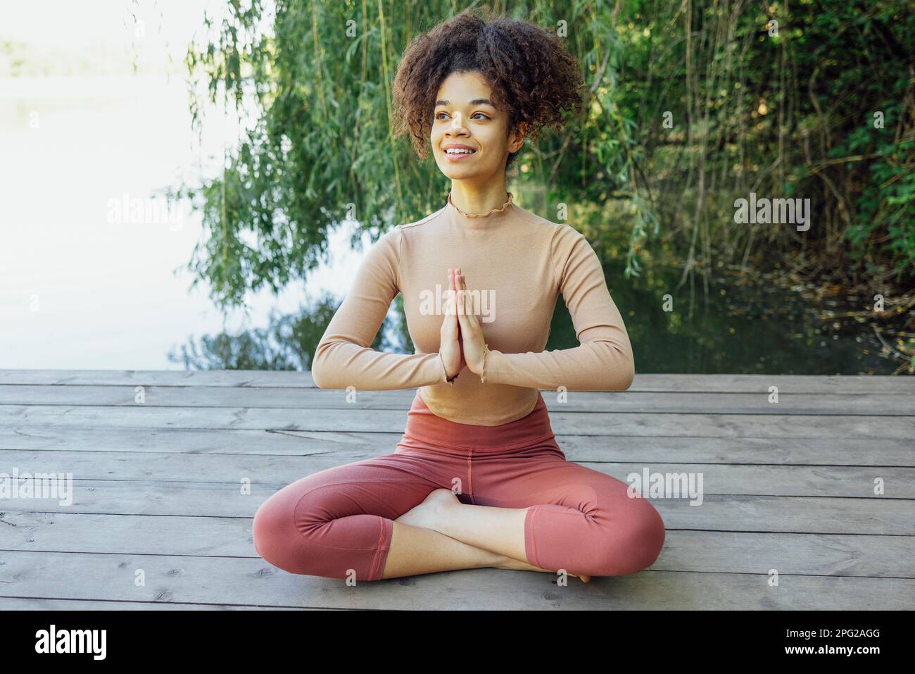 African american young girl is doing yoga asana in park. Smiling female ...