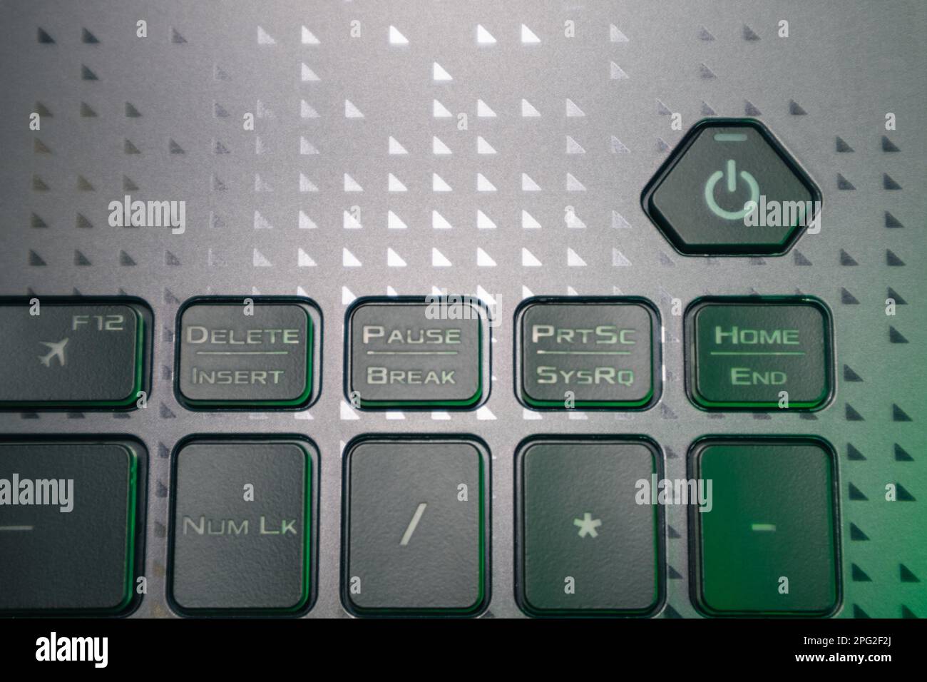 Turn on and off power key in green light. Gaming grey notebook keyboard close-up. Tech, IT, computer science background Stock Photo