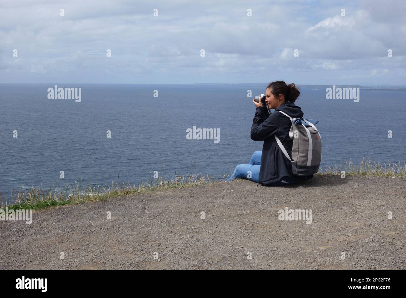 young woman taking photographs at Cliffs of Moher, ireland Stock Photo