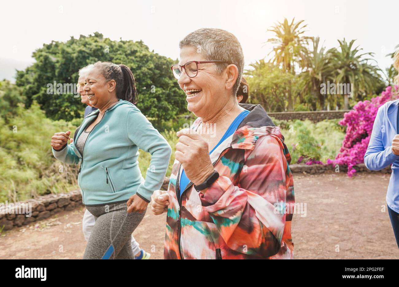 Fit senior people running at city park - Group of elderly friends doing sport workout together outdoor - Main focus on center mature woman face Stock Photo