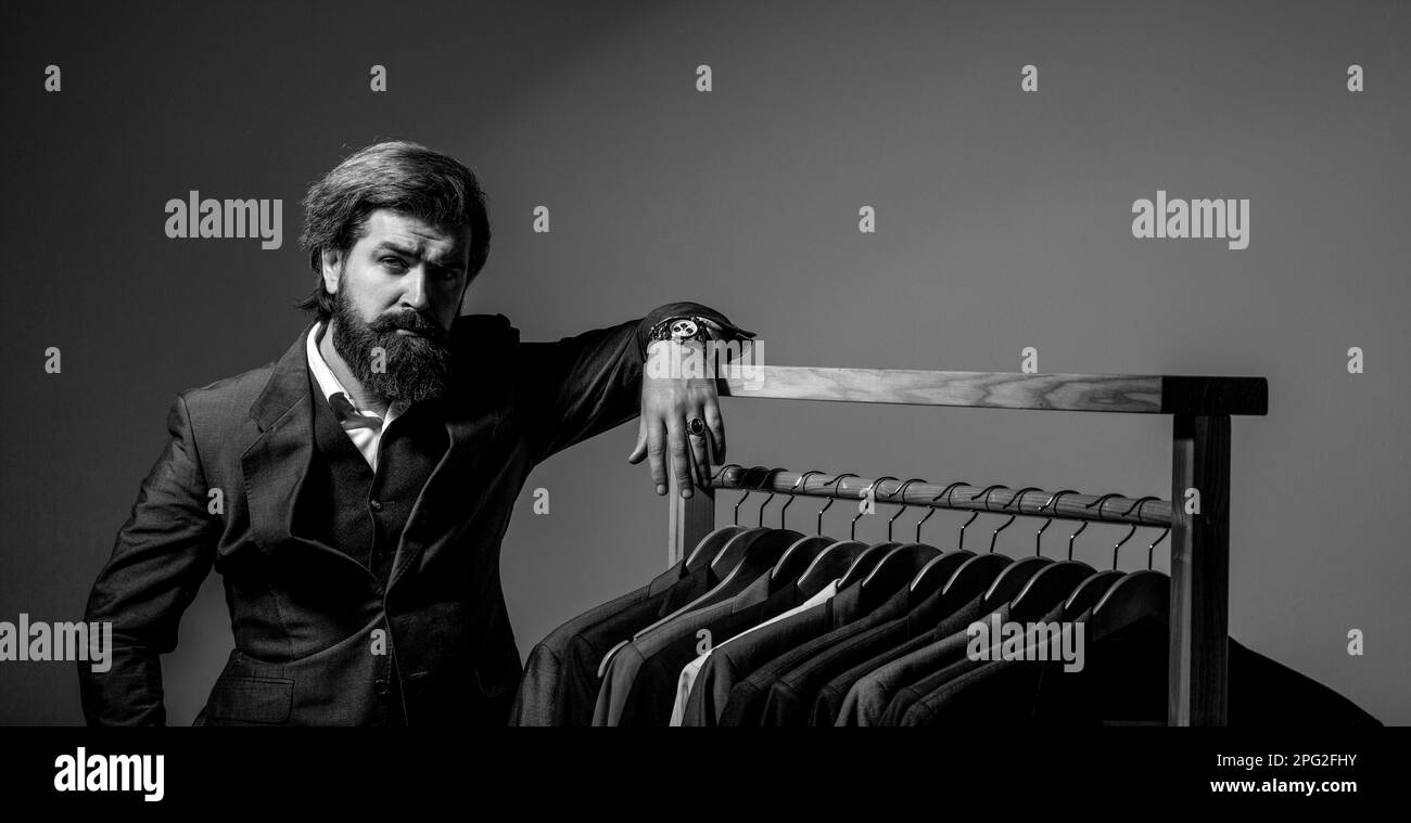 Male suits hanging in a row. Men clothing, boutiques. Man suit, tailor in his. Tailor, tailoring. Black and white Stock Photo
