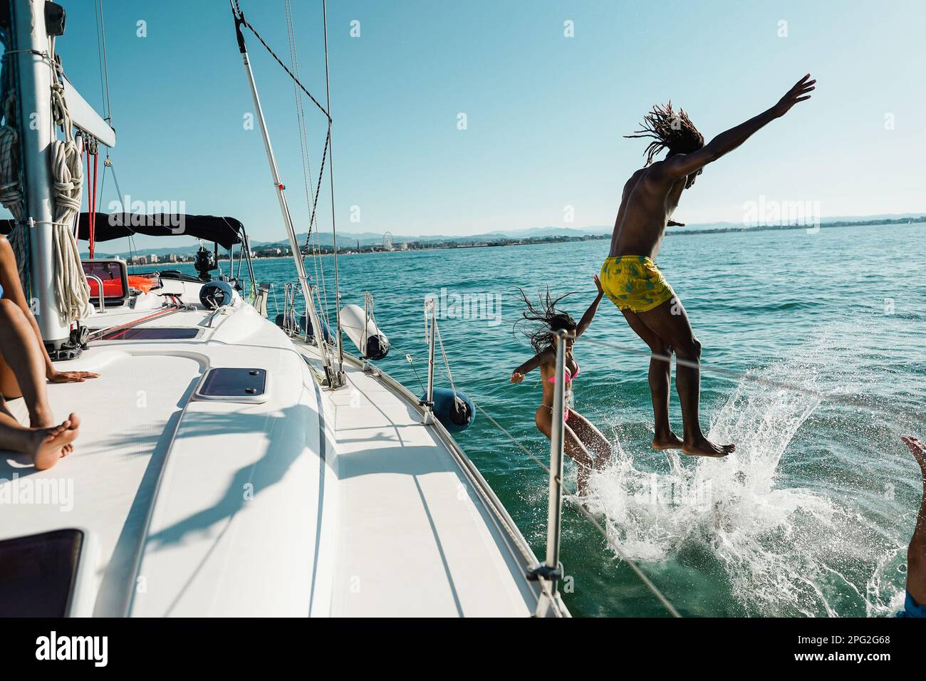 Happy friends diving from sailing boat into the sea - Focus on girl face Stock Photo