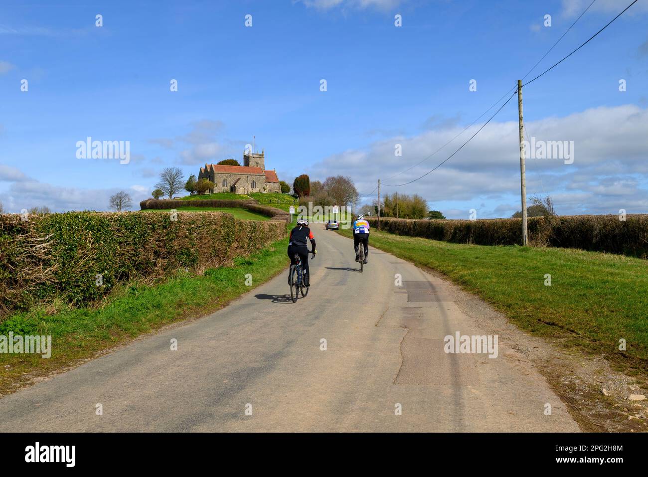 Cyclists near St Arilda church on a hill, Oldbury-on-Severn, South Gloucestershire, England, UK Stock Photo