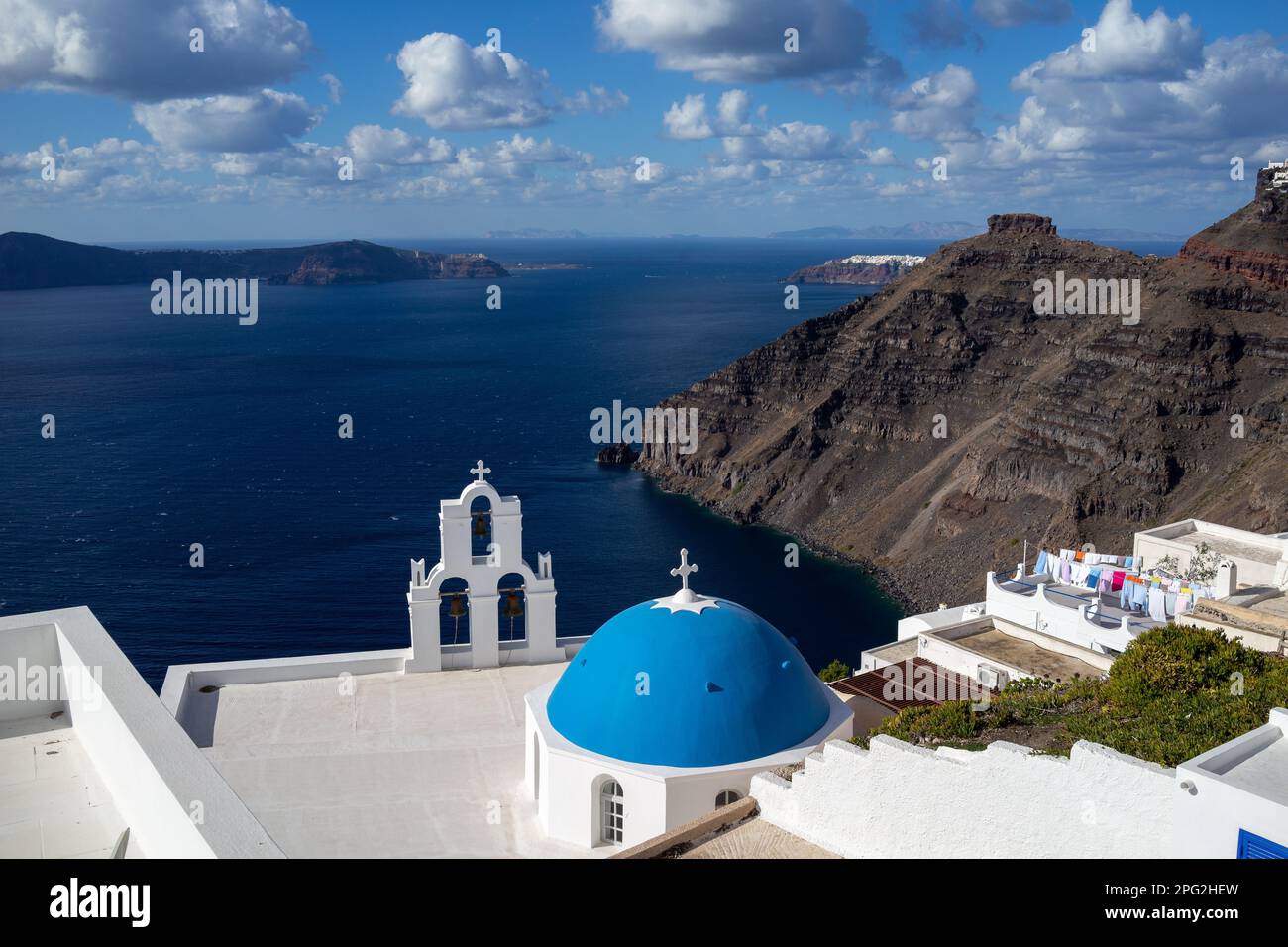 A blue-domed church atop a hillside overlooking the sea in Fira, Santorini, Greece. Stock Photo