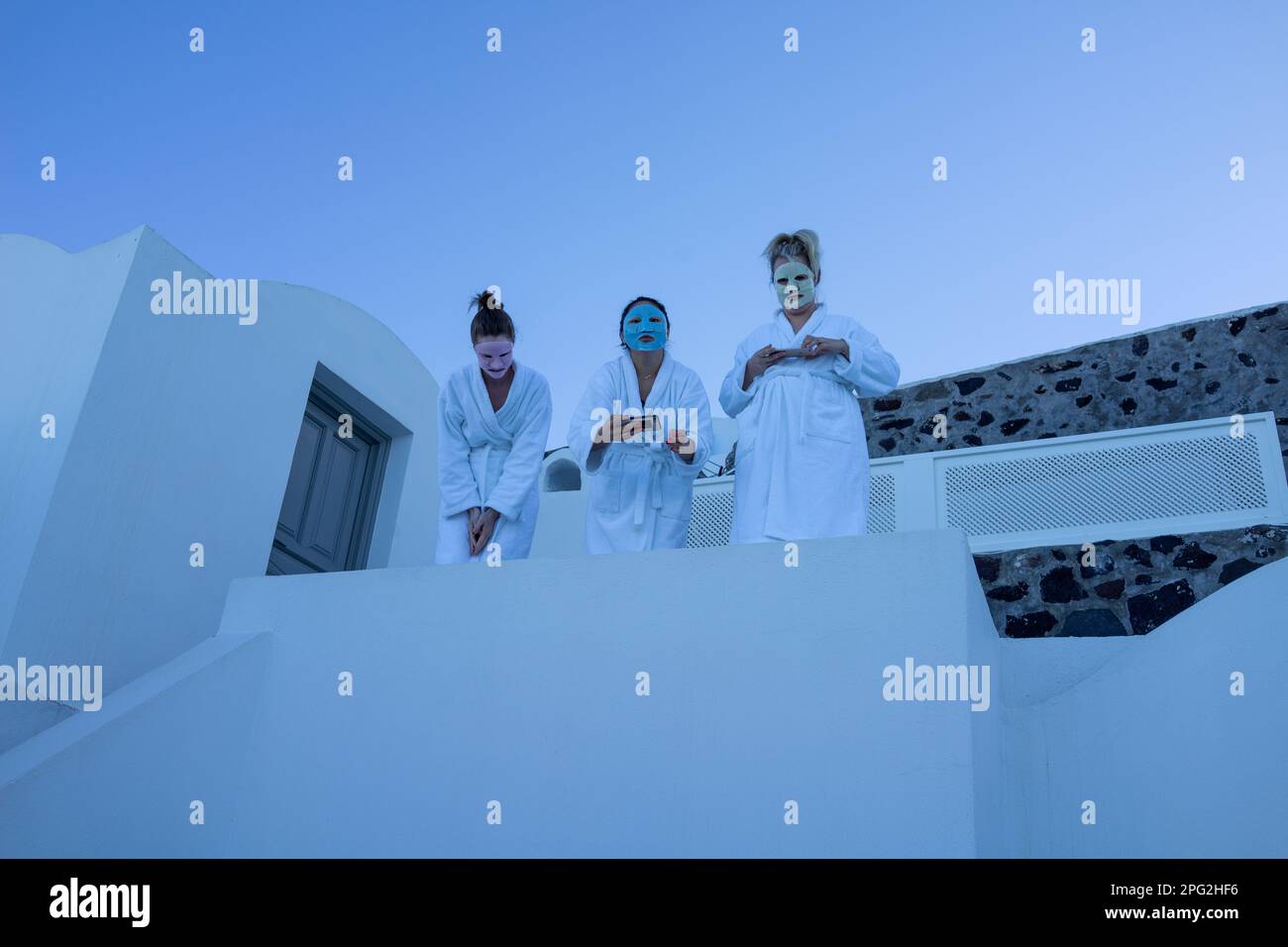 The three women in face masks and robes standing in a white building in