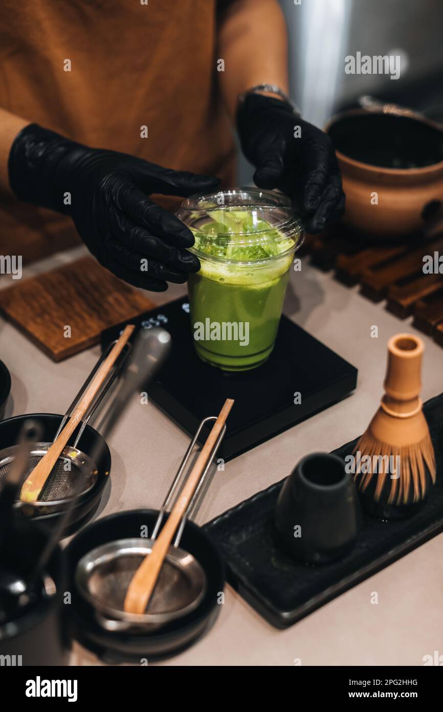 Matcha Japanese green tea making process. Female hands, plastic glass