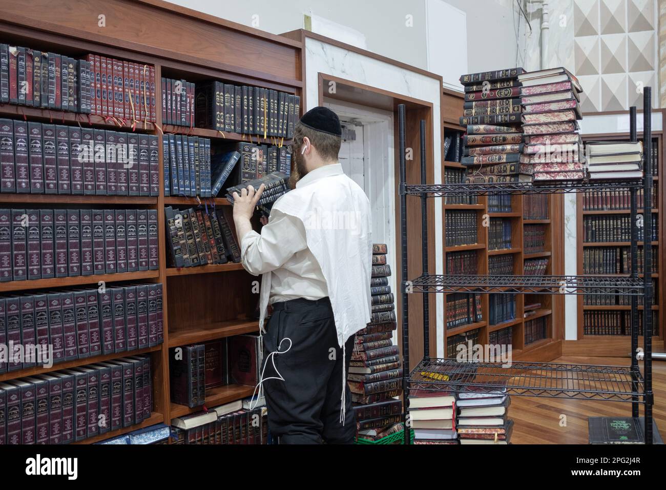 A sexton at a synagogue removes volumes of Exodus & adds volumes of Leviticus so worshippers could keep track during Torah readings. In New York City. Stock Photo